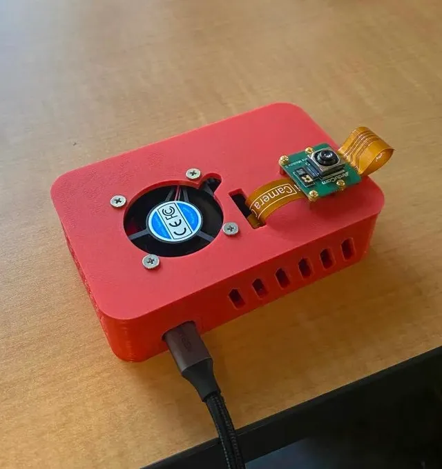 The 3D-printed head-mounted enclosure holding a Raspberry Pi 5 with an Arducam camera on the lid.